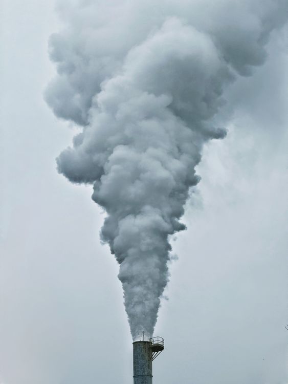 Chimenea industrial emitiendo humo denso al aire, representando emisiones atmosféricas reguladas por SEMARNAT